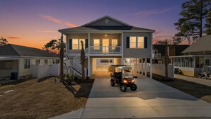 A two-story house with a covered front porch and a golf cart parked in front. - New Crescent Beach luxury home w/pool & NO pet fee (North Myrtle Beach)