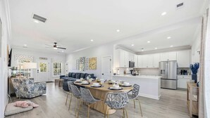 A modern kitchen with white cabinetry, a central island, and stainless steel appliances. - New Crescent Beach luxury home w/pool & NO pet fee (North Myrtle Beach)