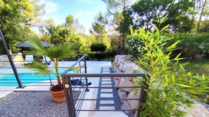 Zona de piscina con una verja de metal, una palmera y un muro de piedra.