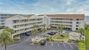 Un hôtel à plusieurs étages doté d’un parking, de palmiers et offrant une vue sur l’océan.