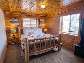 Une chambre dans une cabane en bois, avec un lit, deux lampes de chevet et une fenêtre.