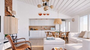 Un salón amplio con un sofá blanco, una mesa de comedor con sillas, y una cocina al fondo.