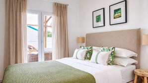 Habitación de hotel con cama, cortinas, vistas al exterior y dos cuadros en la pared.