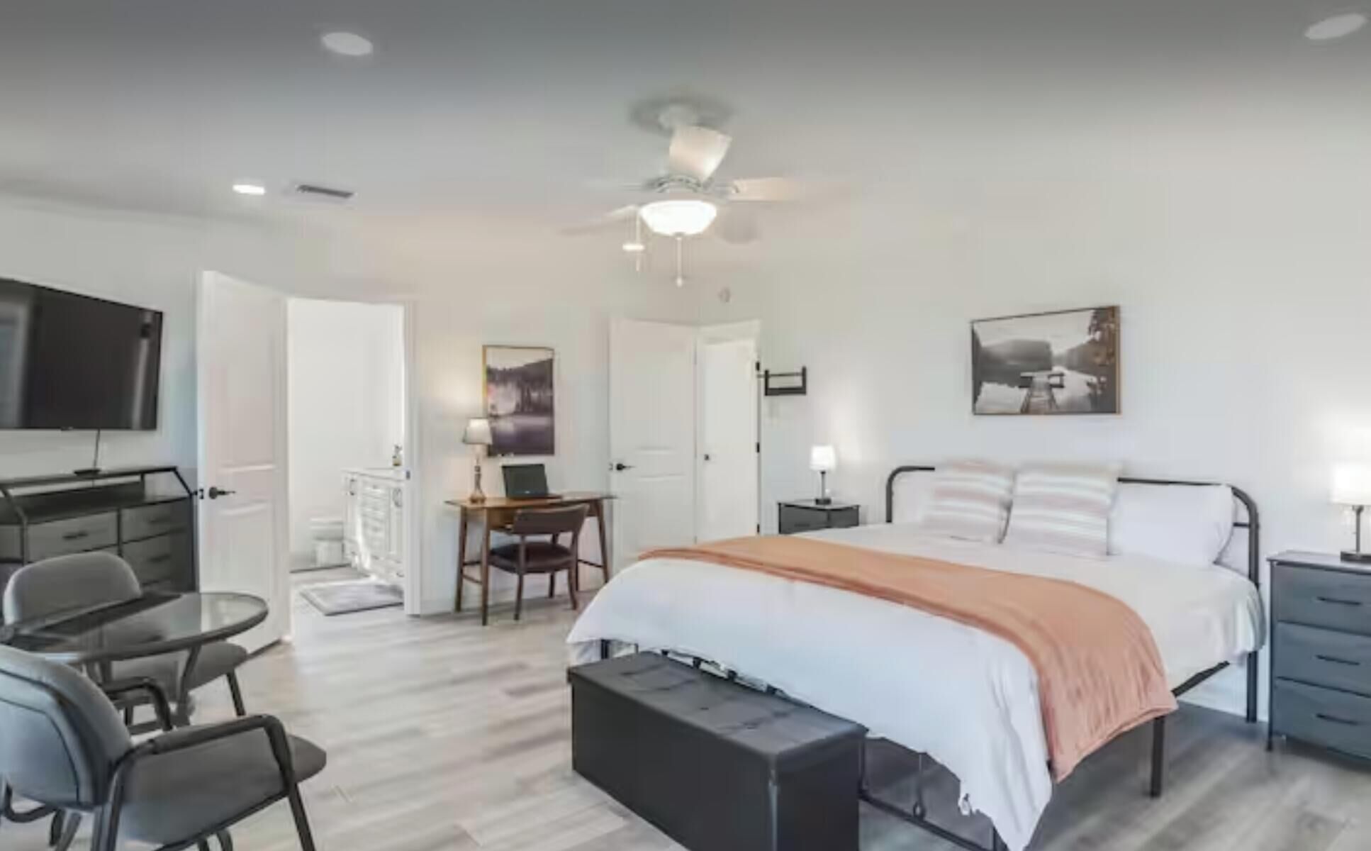 A bedroom with a bed, bedside tables, a desk, a chair, and a television.