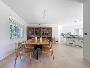 Un'ampia sala da pranzo con un grande tavolo in legno e sedie, circondata da mobili in legno con vetrate.