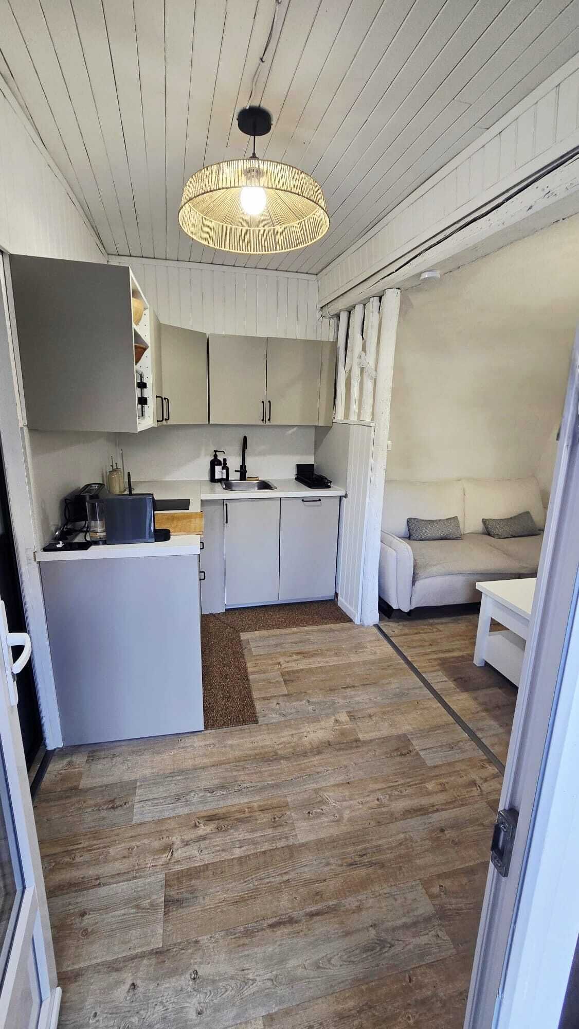 A compact kitchen with white cabinetry, a central island, and a hanging light fixture.
