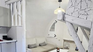 Una habitación con kitchenette, un sofá, una mesa de centro y una pared de piedra.
