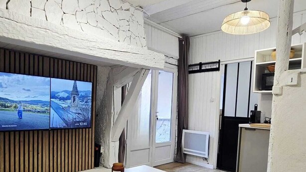 Una sala de estar con televisor, sofá, mesa de centro y zona de cocina.