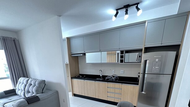 A modern kitchen with grey cabinets, a stainless steel refrigerator, and a dining area with a glass table and grey chairs. - Top 10 - Gleba Palhano (most prestigious neighborhood in Lda), Air, spotless, comfortable and beautiful. (Londrina)