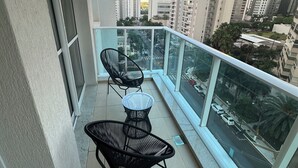 A balcony with two black chairs and a small table, overlooking a cityscape with tall buildings and a road. - Top 10 - Gleba Palhano (most prestigious neighborhood in Lda), Air, spotless, comfortable and beautiful. (Londrina)