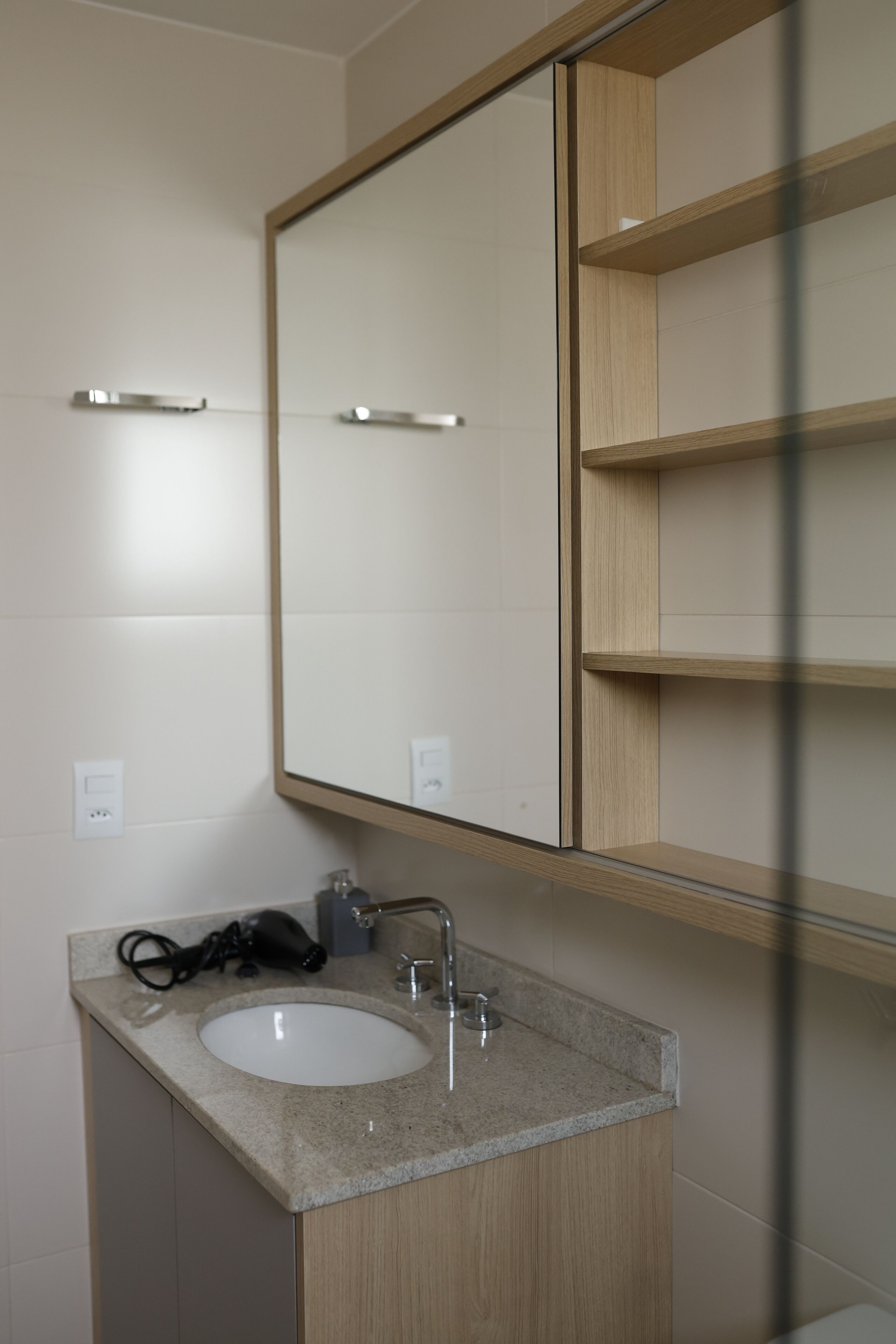 Un baño moderno con un espejo grande, un lavabo y un secador de pelo en la encimera.