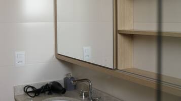 Un baño moderno con un espejo grande, un lavabo y un secador de pelo en la encimera.