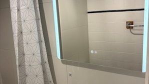 A modern bathroom with a geometric patterned shower curtain, a large mirror, a white sink, and a towel rack. - Le petit Toulousaing - Capitole apartment (Toulouse)