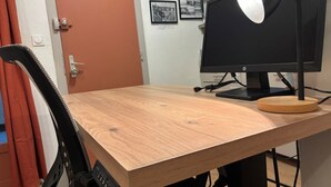 A wooden desk with a monitor and a lamp, a chair, and a door in the background. - Le petit Toulousaing - Capitole apartment (Toulouse)