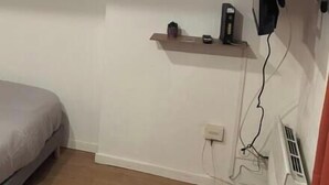 A room with a bunk bed, a small shelf with a fan, a TV mounted on the wall, and a heater. - Le petit Toulousaing - Capitole apartment (Toulouse)