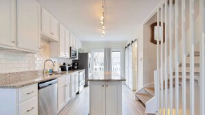 A modern kitchen with white cabinets, granite countertops, and a central island. - Harbour Bay 5, Beautiful 3BR Modern Bayside Townhome, Quiet! (Ocean City)