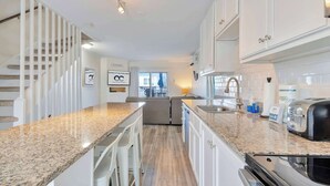A modern kitchen with granite countertops, white cabinetry, and a built-in oven. - Harbour Bay 5, Beautiful 3BR Modern Bayside Townhome, Quiet! (Ocean City)