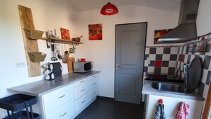 Uma cozinha compacta com armários brancos, micro-ondas, pia e um pequeno espaço de refeições.