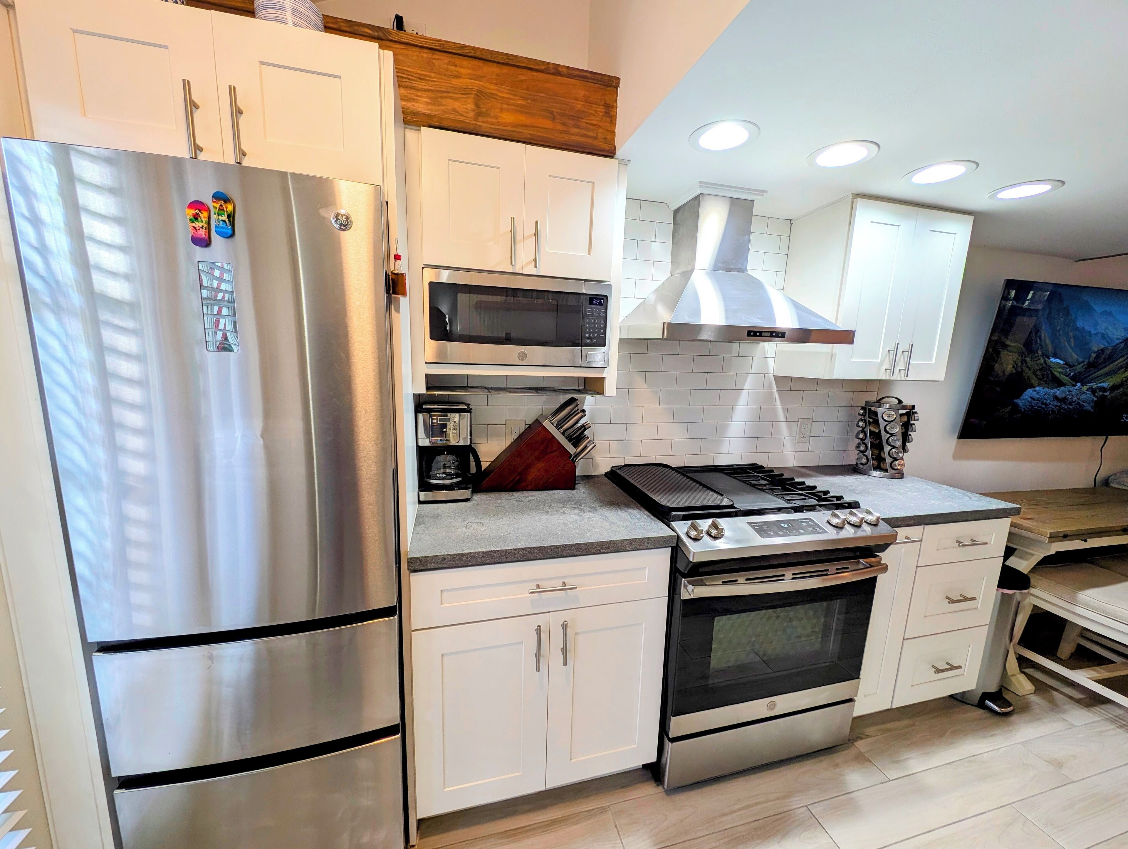 A modern kitchen with stainless steel appliances, white cabinetry, a microwave, a gas stove, and a built-in oven.