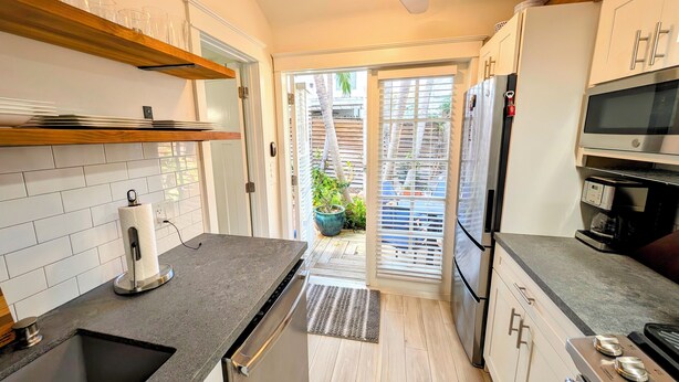 Een moderne keuken met een inbouwvaatwasser, roestvrijstalen apparatuur en een houten plank.