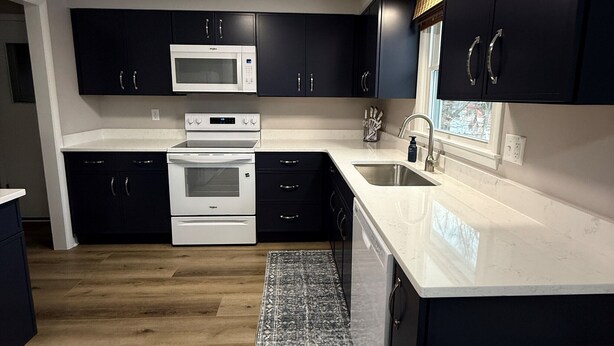 A modern kitchen with dark cabinets, white countertops, a microwave, oven, and dishwasher. - Ann's Adobe - 2 Bdrm Apartment in Mansfield, OH - close to Lexington & Ontario (Mansfield)
