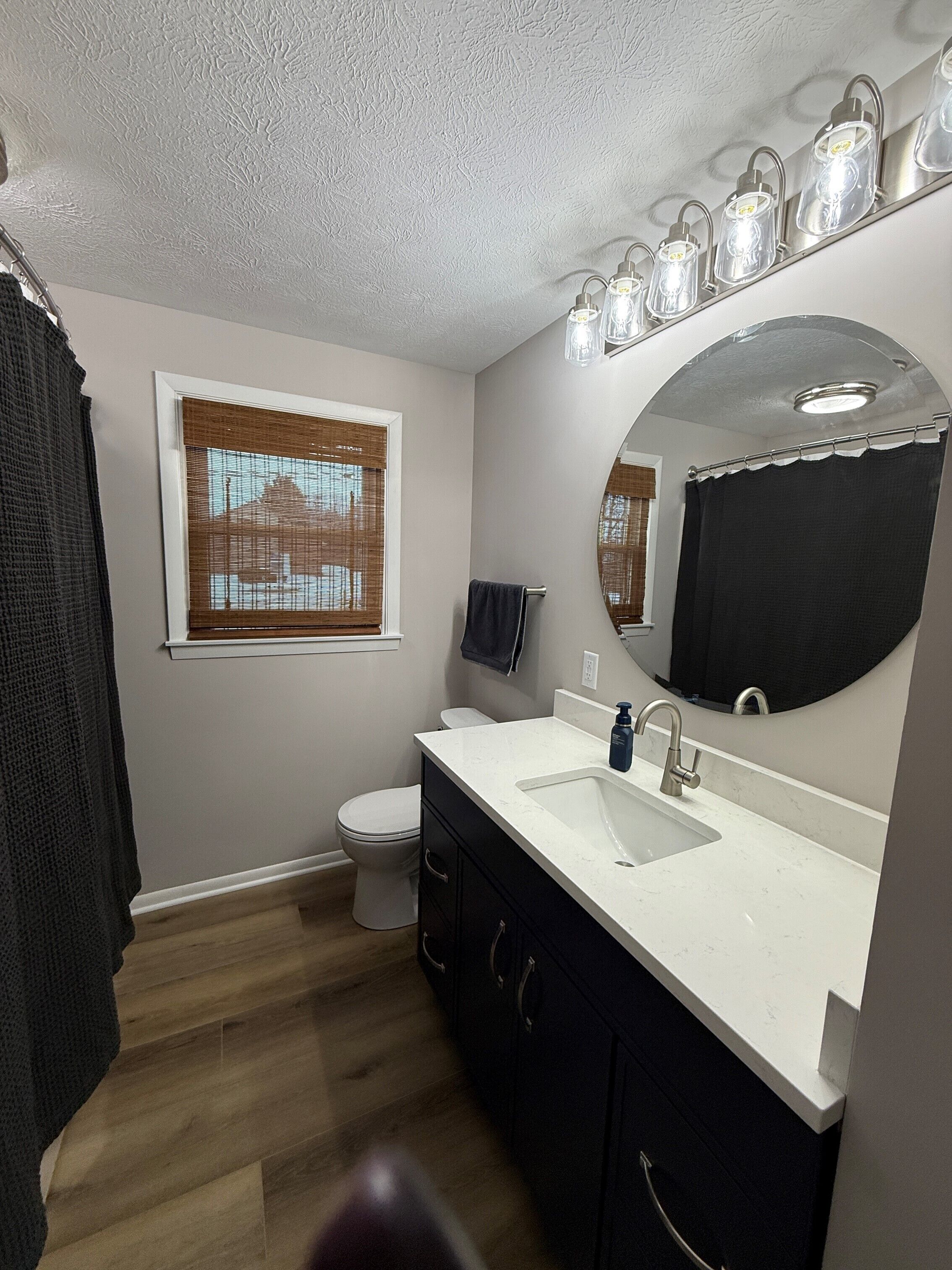 A bathroom with a toilet, sink, and mirror.