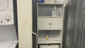 Een kleine badkamer met toilet, een plank met toiletartikelen en een wasmachine.