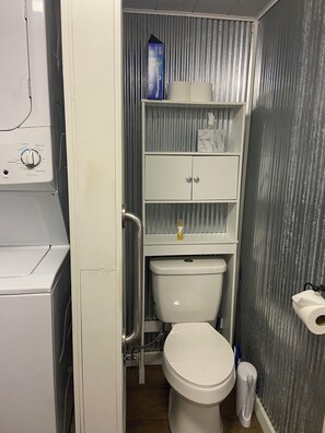 Ein kleines Badezimmer mit Toilette, Ablage für Toilettenartikel und einer Waschmaschine.