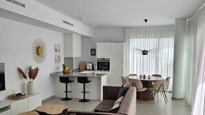 Un soggiorno moderno con divano, tavolino da caffè e zona pranzo con sedie.