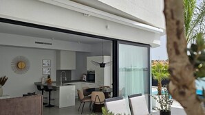 Una cucina moderna con zona pranzo, ampie porte scorrevoli in vetro e vista sulla piscina.