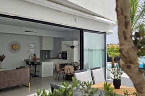 A modern kitchen with a dining area, large sliding glass doors, and a view of the pool. - Villa LUISA La Marina Alicante with private pool 3 bedrooms & 3 bathrooms (VC)