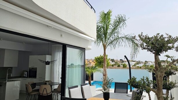Una villa moderna con zona pranzo, piscina e vista sul paesaggio.