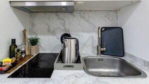Une cuisine moderne dotée d’une plaque de cuisson à induction noire, d’un évier en acier inoxydable et d’un dosseret en marbre.