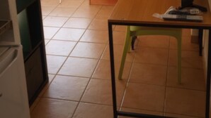 Ein Zimmer mit Holztisch, grünem Sessel, Kleiderschrank und Meerblick.