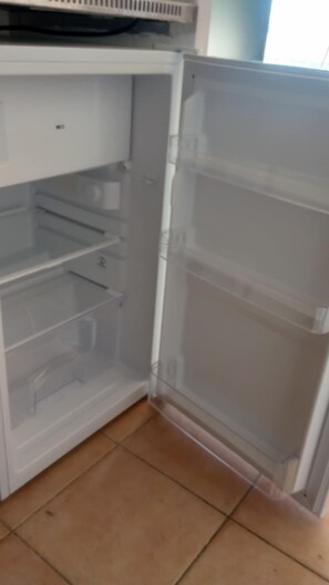 Un réfrigérateur ouvert, avec des étagères transparentes et un compartiment congélateur.