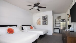 Hotelkamer met twee bedden, een plafondventilator, een koelkast, een magnetron en een flatscreen-televisie.
