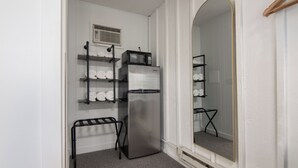 Een compacte kitchenette met een roestvrijstalen koelkast, een magnetron en een klein rek met handdoeken.