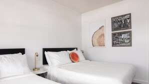 Een hotelkamer met twee bedden, een nachtkastje, een muurlamp en twee ingelijste foto's.