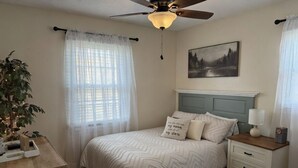 Ein Schlafzimmer mit Bett, Nachttisch und Deckenventilator.
