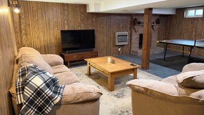 Ein Wohnzimmer mit einem Flachbildfernseher, einem Tischtennisschrank und einem Kamin aus Ziegeln.