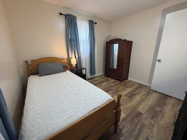 Une chambre à coucher avec un lit en bois, une table de chevet avec une lampe, une armoire et une porte.
