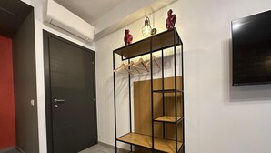 A room with a black wardrobe, a wooden shelf unit with hangers, and a mounted television. - Silent Airport Room 5 minutes from BGY airport and Bergamo city center (Azzano San Paolo)