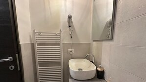 A modern bathroom with a white sink, a towel rack, a mirror, and a small trash bin. - Silent Airport Room 5 minutes from BGY airport and Bergamo city center (Azzano San Paolo)