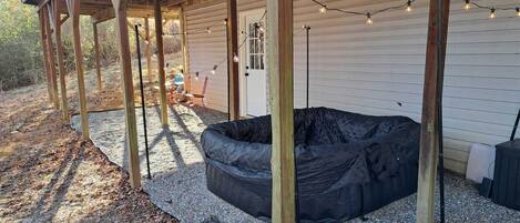 An outdoor deck with a black outdoor seating area, wooden beams, and string lights.