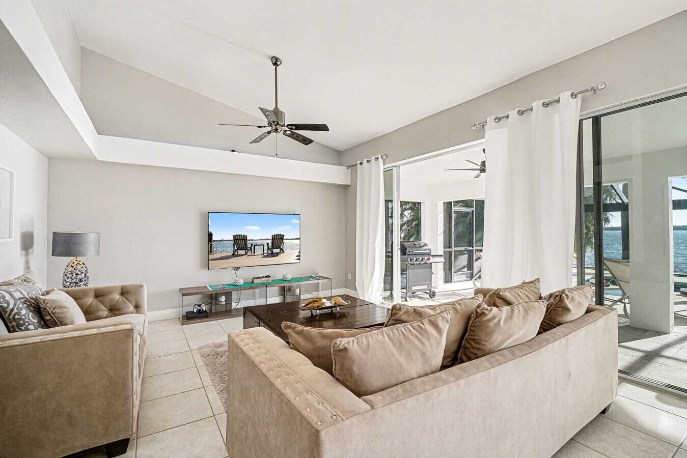 Ein modernes Wohnzimmer mit einer großen Couch, einem Couchtisch, einem Fernseher und einem Deckenventilator.