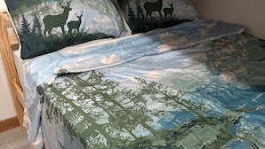 A bunk bed with camouflage bedding and forest-themed pillows. - River Valley House Paradise (pigeon forge)