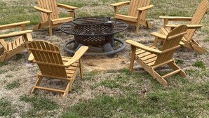 A circular fire pit surrounded by wooden Adirondack chairs in a grassy outdoor area. - River Valley House Paradise (pigeon forge)