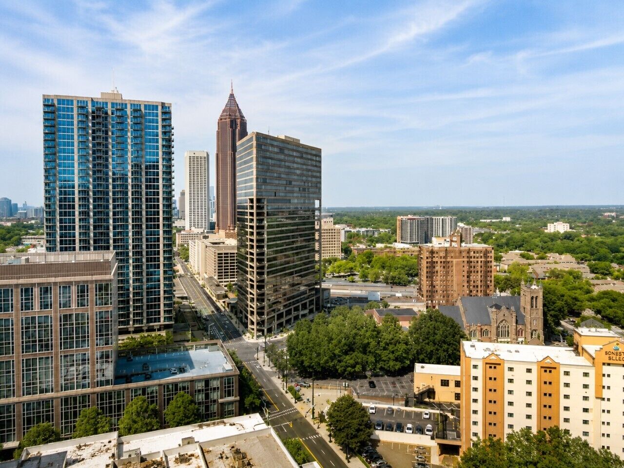 A cityscape with modern high-rise buildings, a church, and a parking lot.