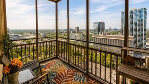 A balcony with a view of a cityscape, including high-rise buildings and greenery. - Modern Designed DTWN Condo with a 99% Walk Score (Atlanta)