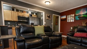 A living room with a black leather sofa, a small coffee table, and a kitchen in the background. - Modern Designed DTWN Condo with a 99% Walk Score (Atlanta)